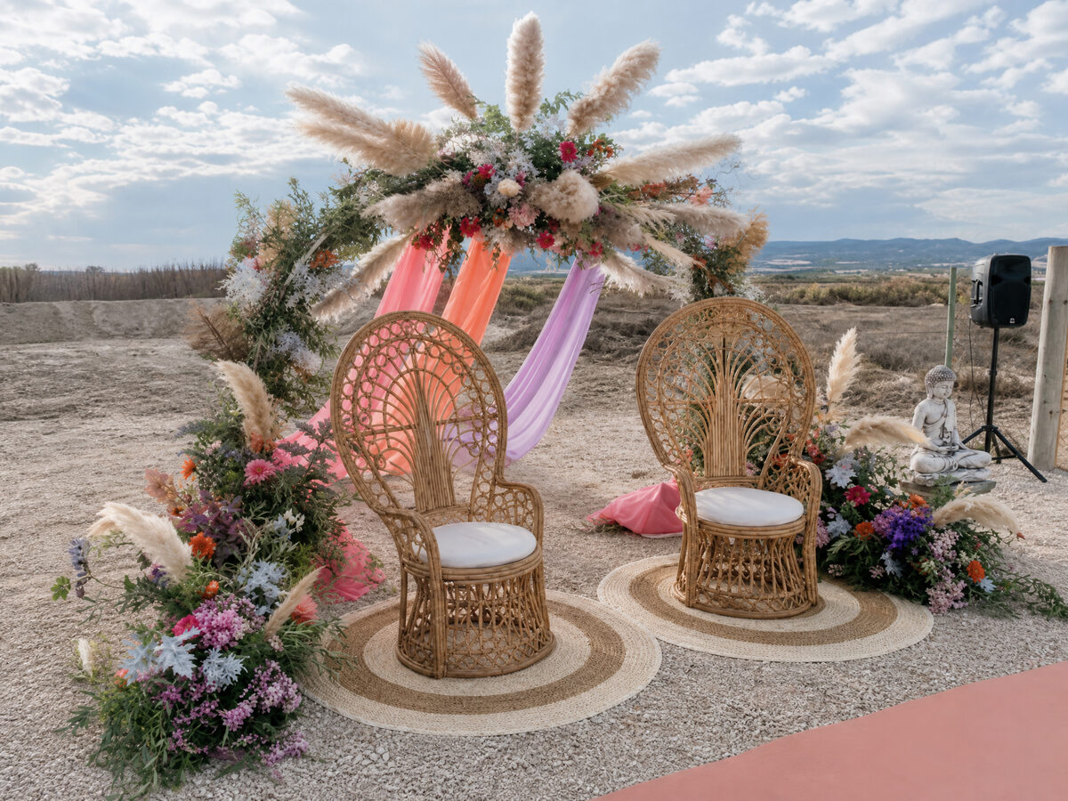 Decoración de boda con arco floral y sillas de mimbre